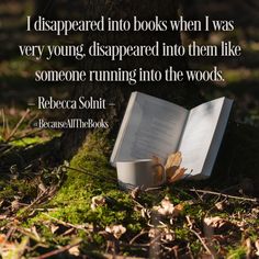 an open book laying on the ground next to a tree and moss covered ground with leaves