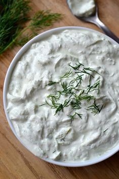 a white bowl filled with sour cream and topped with fresh dill sprigs