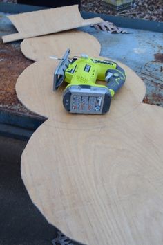 a cordless driller sitting on top of a piece of plywood that is laying on the ground