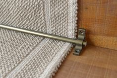 a close up of a metal object on a wooden surface with a knitted cloth in the background