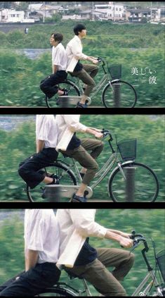 two people riding on the back of a bike in front of a field with grass