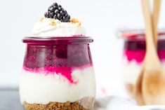 two desserts in glass jars with spoons next to them on a white table