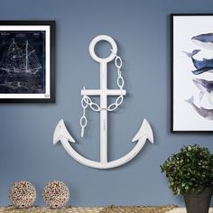 an anchor is hanging on the wall next to two pictures and a potted plant