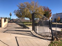 an iron gate is open on the sidewalk