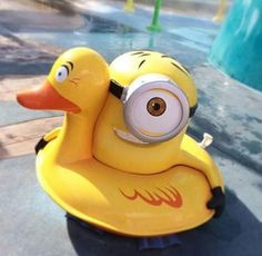 a yellow rubber ducky toy sitting on top of a sidewalk next to a swimming pool