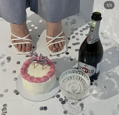 a woman standing next to a cake and bottle of beer