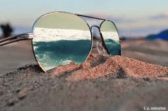 a pair of sunglasses sitting on top of a sandy beach