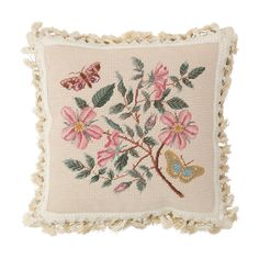 a pink pillow with flowers and butterflies on the front, fringe trimming around the edges