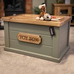 a toy box with a stuffed giraffe sitting on it's top and the word toy box written in wood