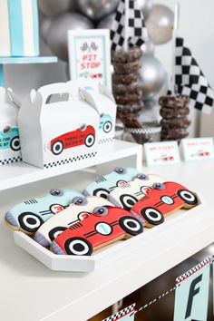 a table topped with boxes filled with cookies and cars on top of each other next to balloons