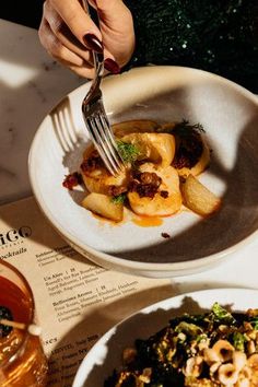 a person is eating food from a bowl on a table with other plates and utensils