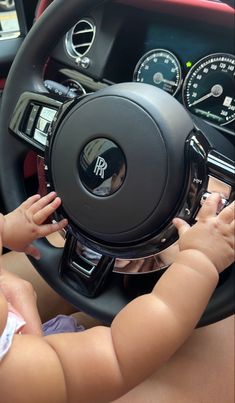 a baby sitting in the drivers seat of a car holding on to a steering wheel