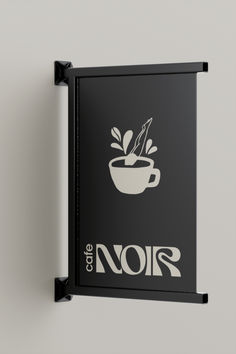 a black and white sign hanging on the side of a wall next to a cup of coffee