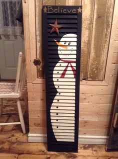 a wooden door with a snowman painted on the front and side panels that say believe