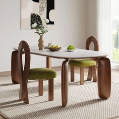 a dining room table with two chairs and a bowl of fruit on the table next to it