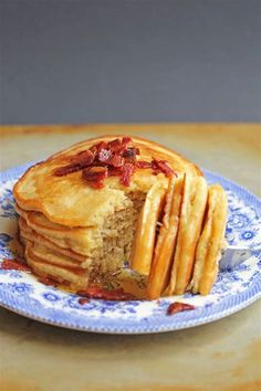 a blue and white plate topped with pancakes covered in bacon