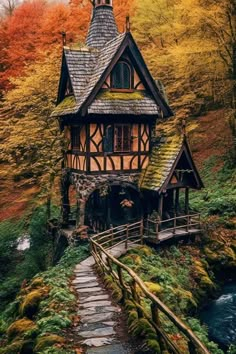 a small house with a steeple on the roof next to a stream and trees