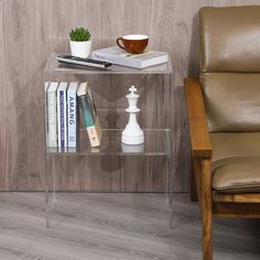 a glass table with books and a chess piece on it next to a leather chair