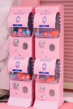 three pink candy machines are stacked on top of each other in front of a wall