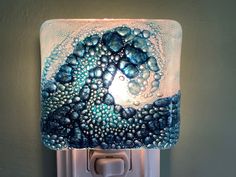 a light that is on the side of a wall next to a green wall with blue and white designs