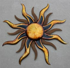 a metal sun with yellow and black stripes on it's face, against a gray background