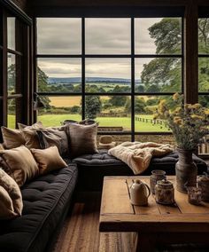 a living room filled with lots of furniture next to a large window covered in windows