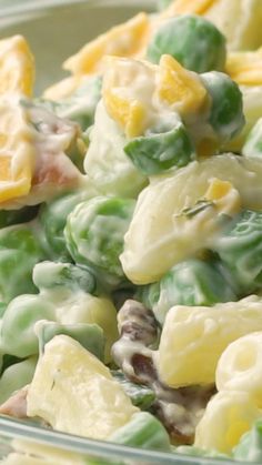 a close up of a bowl of food with peas, oranges and macaroni salad