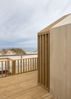 a wooden deck next to the ocean with a building on one side and a beach in the background