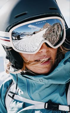 a woman wearing ski goggles while standing in the snow