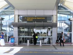 two people standing in front of an airport entrance