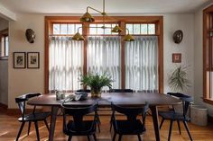 a dining room table with four chairs and a potted plant in the corner on the far side