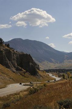 an empty road in the mountains with cars driving on it