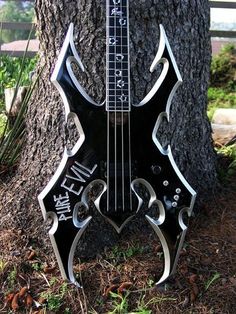 a guitar shaped like a tree in front of a fence