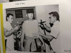 a black and white photo of two men in front of a camera with another man holding a microphone