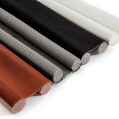 four different colors of fabric are lined up together on a white surface, including black, gray, and orange