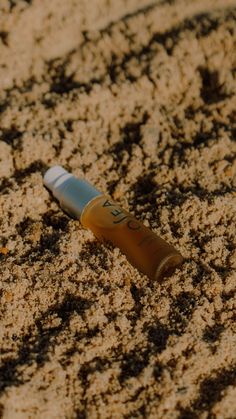 an orange and white toothbrush laying in the sand