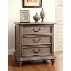 a dresser with three drawers and two pictures on top