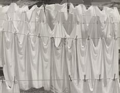 an old black and white photo of clothes hanging out to dry on a line outside