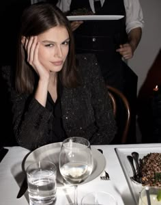 a woman sitting at a table with food and drinks