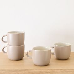 four white cups sitting on top of a wooden table