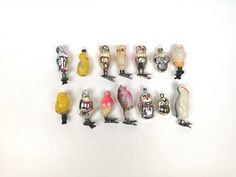 there are many small glass birds sitting on the table together, all different colors and sizes