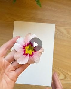 a person is holding a flower in their left hand and pressing it on the paper