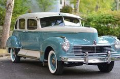 an old blue and white car parked on the street