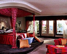 a red canopy bed sitting in the middle of a living room next to two couches