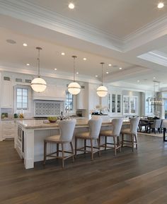 a large open concept kitchen and dining room with wood floors, white cabinets and an island