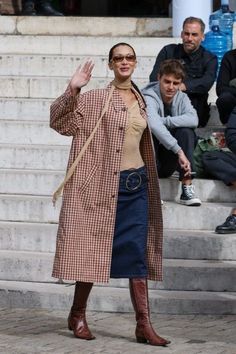 a woman is waving while walking down the street