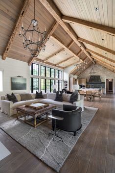 a large open living room with high ceilings and wooden beams on the ceiling is furnished with modern furniture