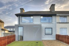 a house with a fence in front of it and grass on the ground next to it