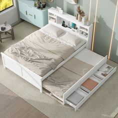 a white bed with drawers underneath it in a room next to a dresser and table