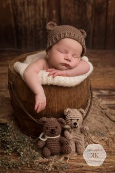 a baby sleeping in a bucket with two teddy bears